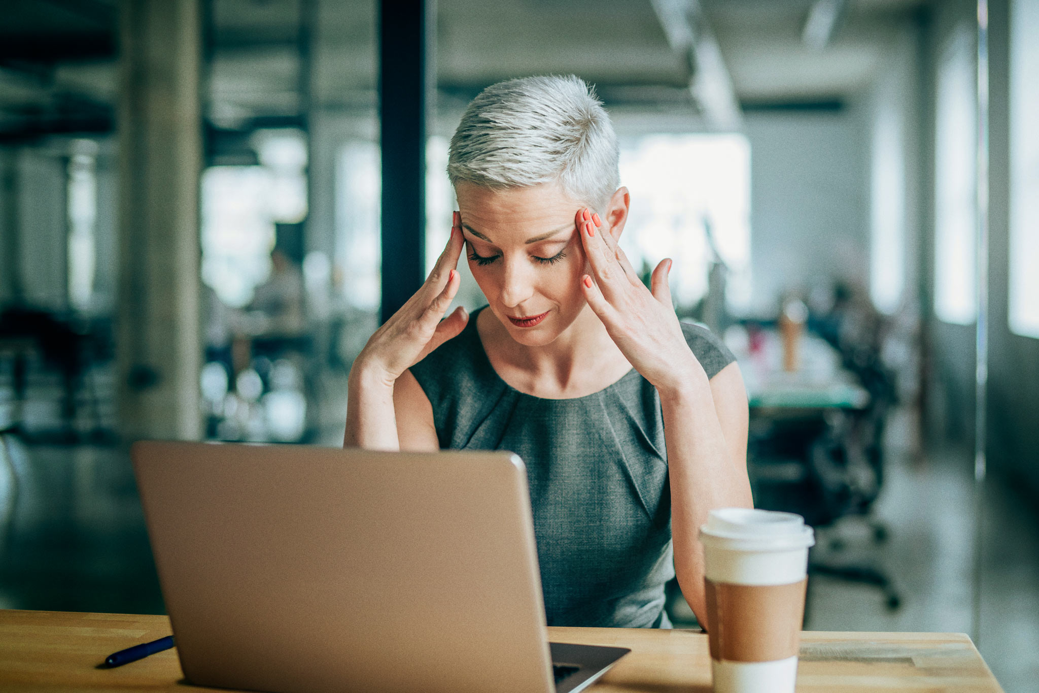 Female entrepreneur with headache sitting at desk. Photo: iStock.com/VioletaStoimenova