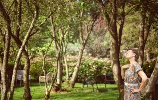 Exterior photo of a smiling Carina Weijma looking up at the canopy of a luscious park.