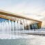 Modern venue with huge glass walls, with a fountain in the foreground.